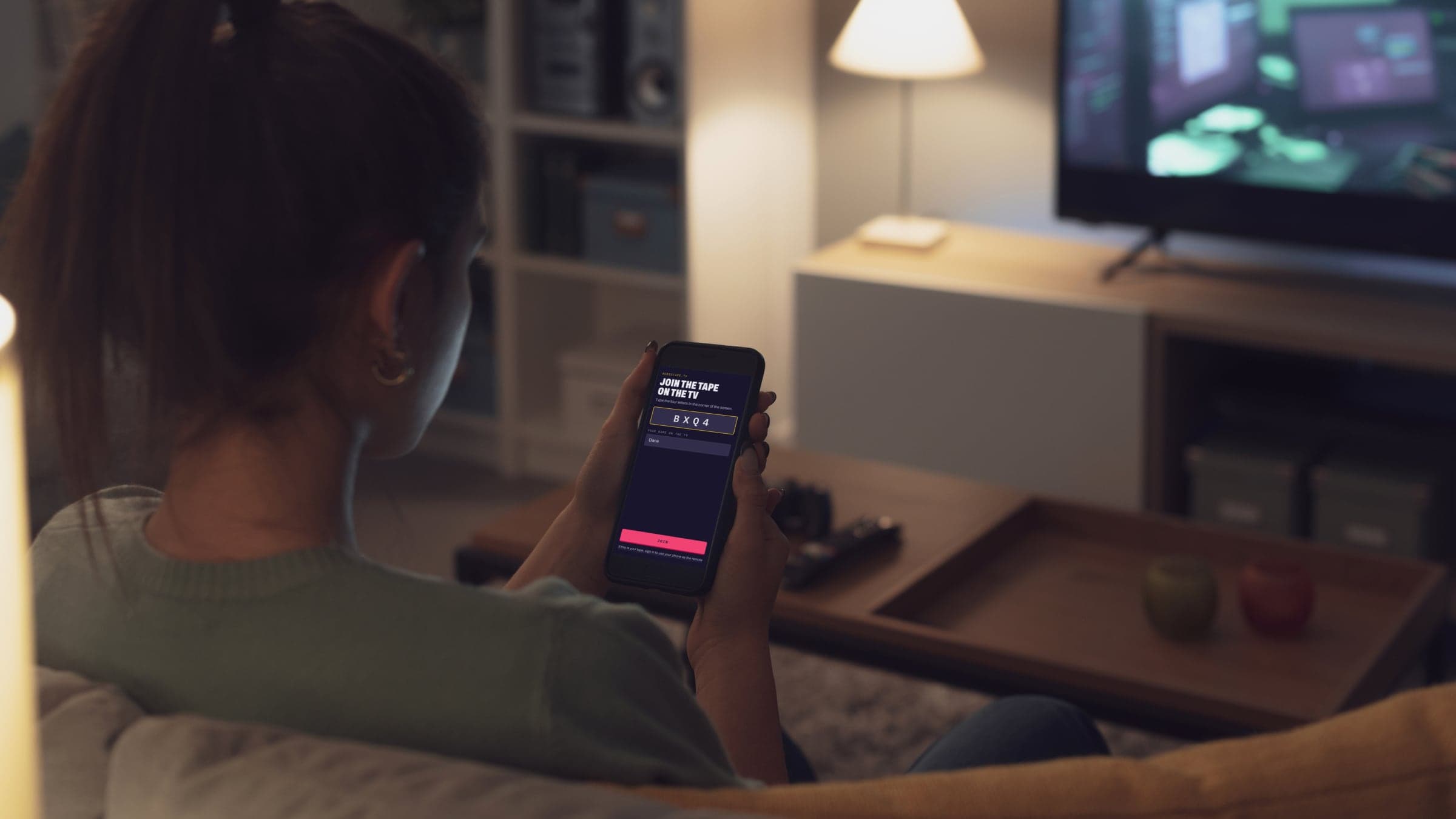 Someone on the couch typing a room's code into the audiotape.tv page on their phone